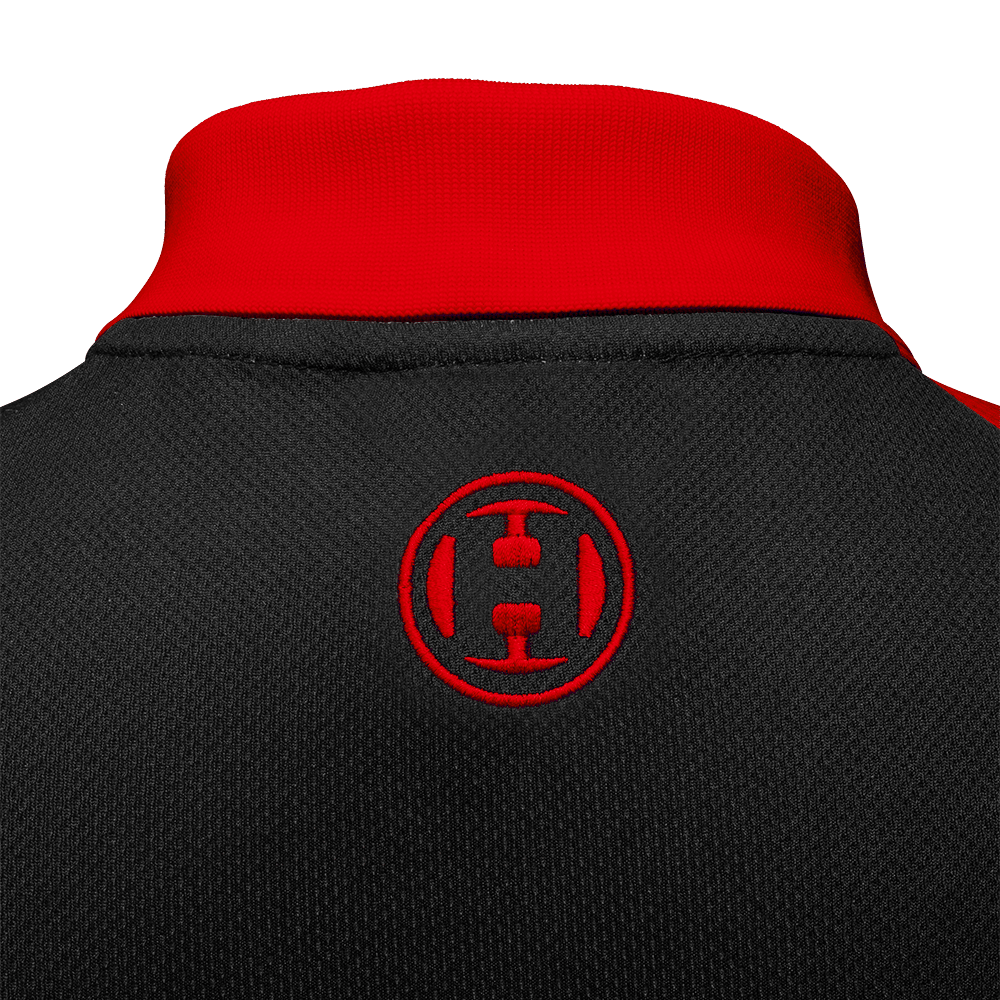Das Bild zeigt den oberen Rückenbereich eines Harrows Rapide Dartshirts in Rot und Schwarz. Auf dem schwarzen Stoff ist ein rotes, rundes Harrows-Logo aufgestickt.