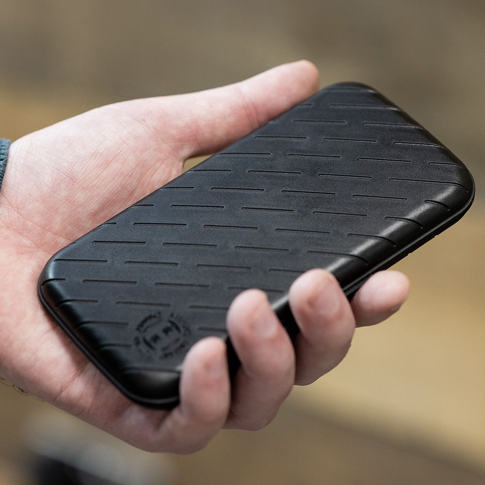 Harrows Slimcase Darttasche Eine Person hält eine schwarze, schlanke Darttasche in der Hand. Die Oberfläche der Tasche hat ein dezentes, gerilltes Muster.